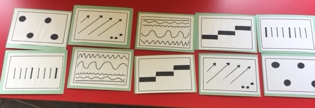A series of graphic symbols made from swell paper mounted on cards. These are laid out on a table in two rows. 